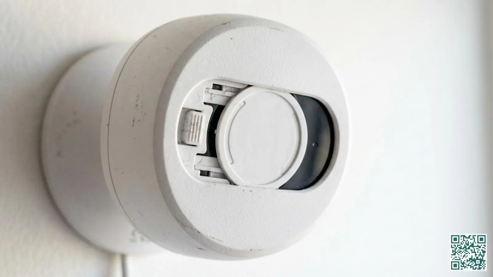 Close-up van een witte binnencamera met een gesloten fysieke privacy shutter die de lens volledig afdekt