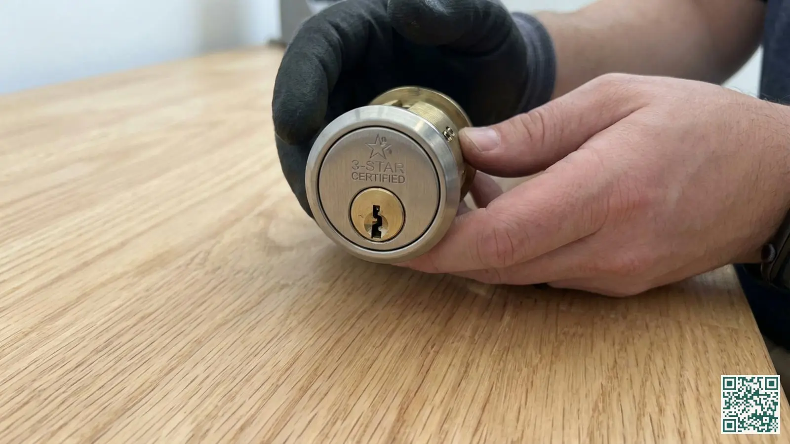 Close-up van een SKG drie sterren cilinderslot met zichtbare boorbeveiliging vastgehouden boven houten oppervlak